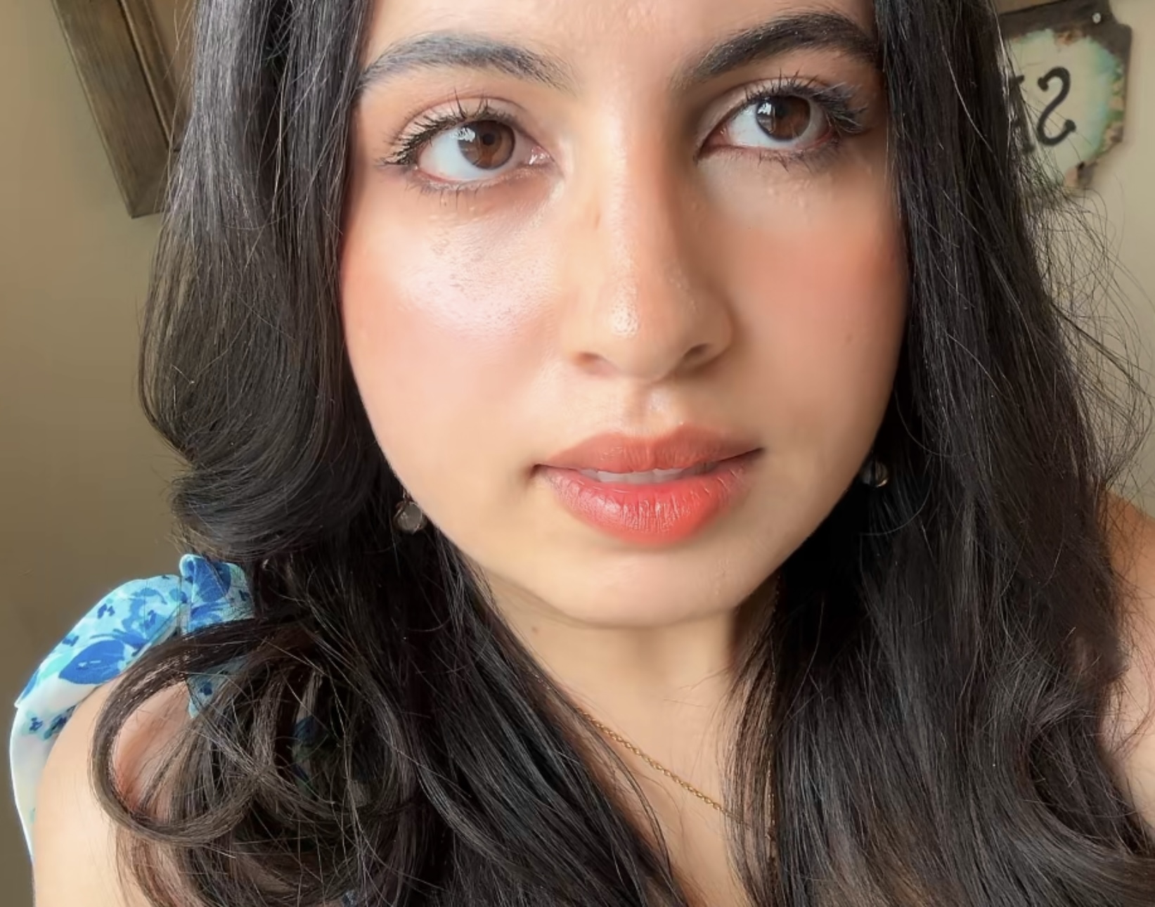 Close-up portrait of a person with long hair, wearing subtle makeup and a blue floral top.