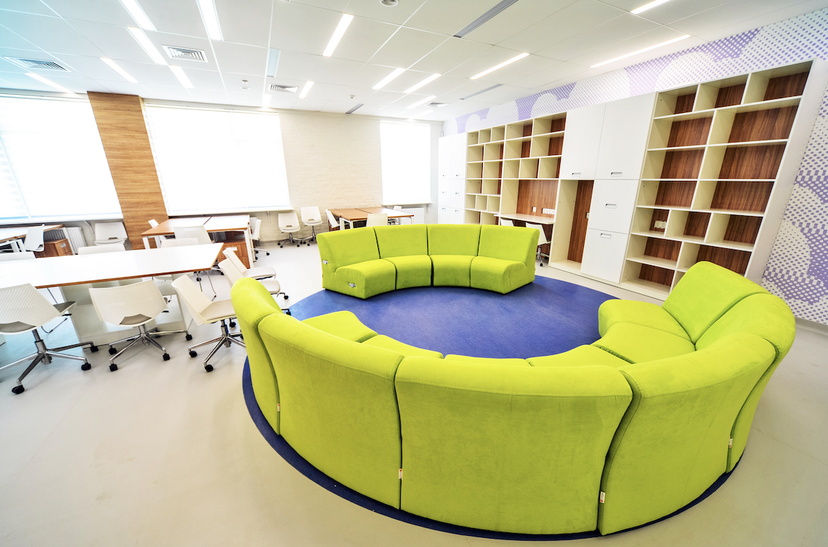 a bright green couch is surrounded by desks and shelves