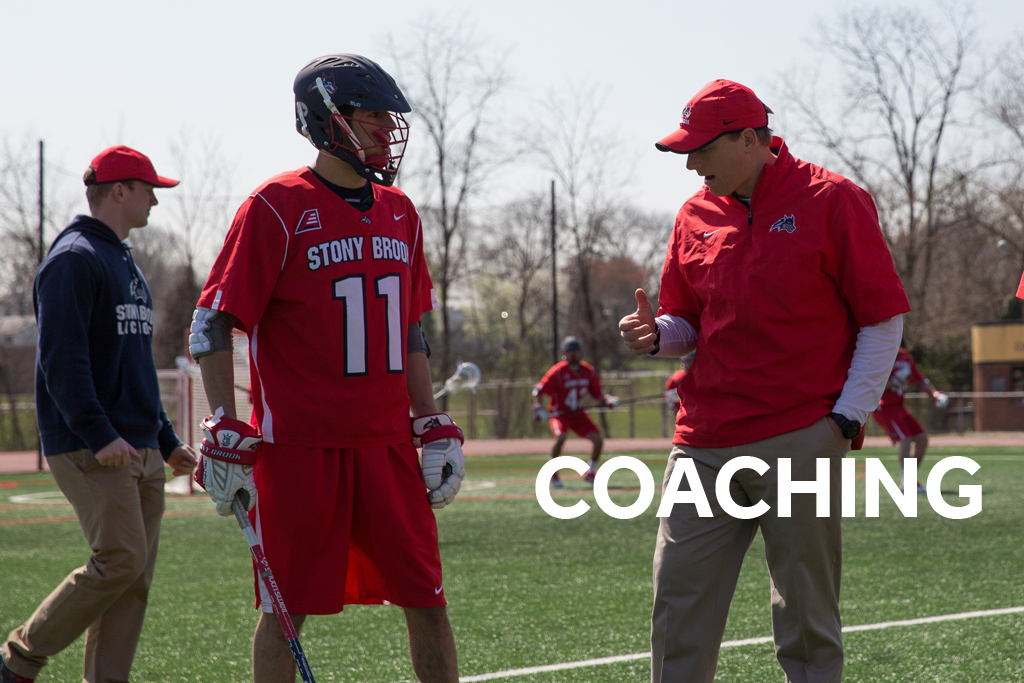 Lacrosse coach speaking with player on the field.